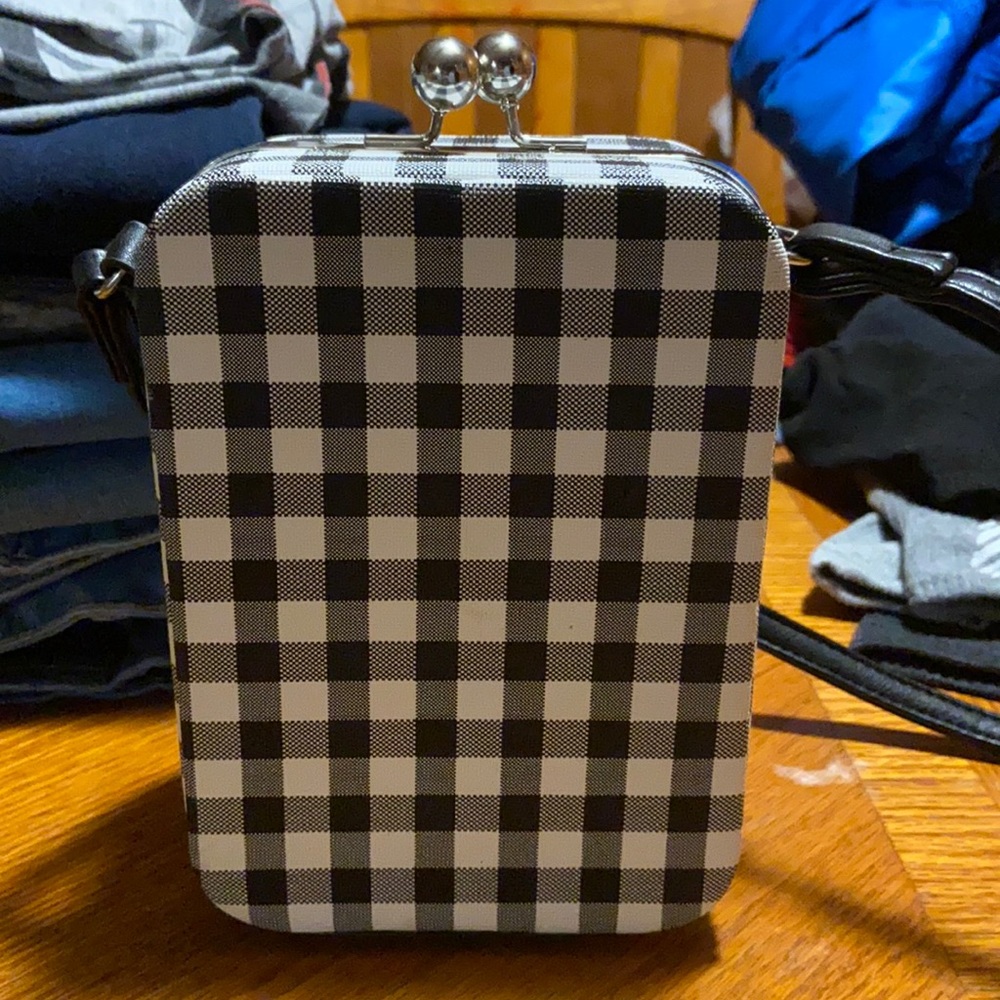 black and white checkered crossbody bag with clip balls that close at the top.